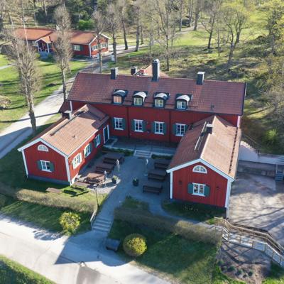 Aerial view of Mässen at Hamra Farm, a traditional red wooden building originally used as a dairy and now serving as the farm’s restaurant, with a courtyard and outdoor seating.