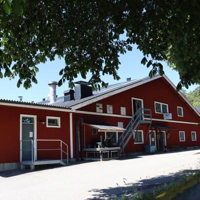R&D barn exterior with red wooden building and entrance area under trees