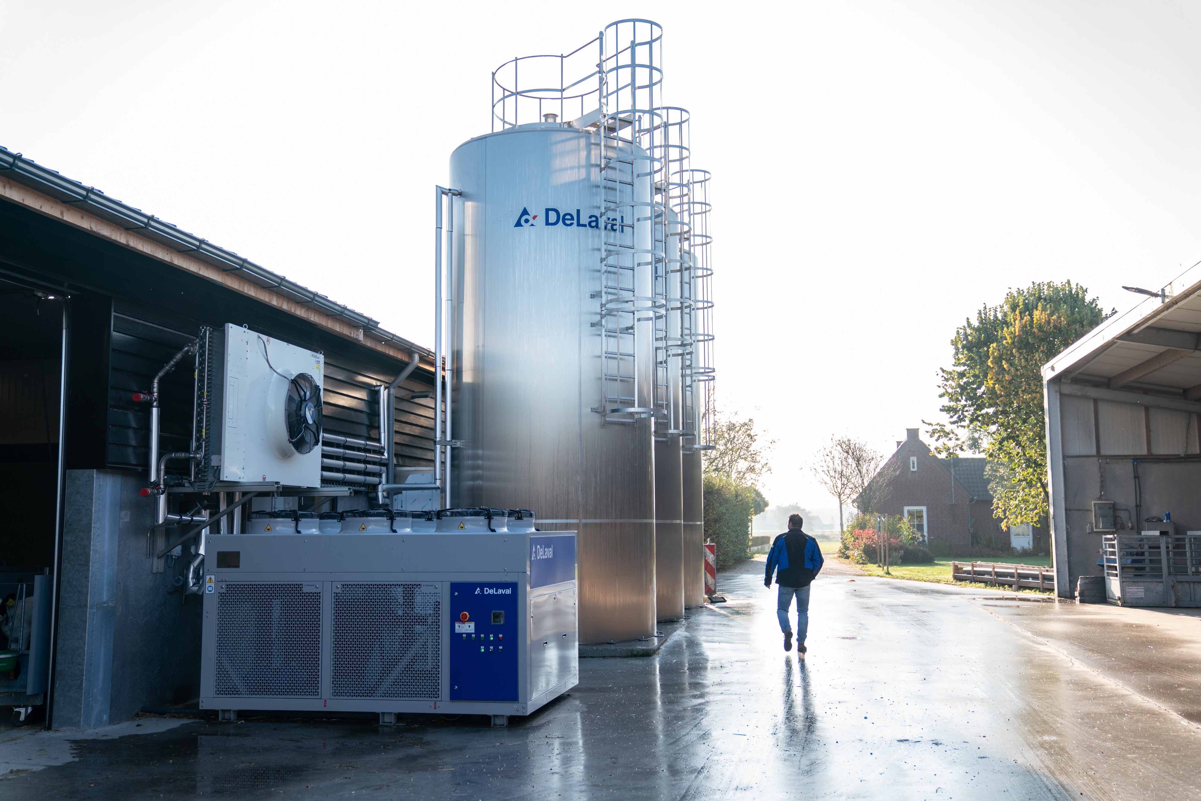 Man lopend naar 3x DeLaval silotanks DX3S en een Compact Water Chiller CWC