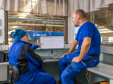 Kund sitter framför en VMS-dator tillsammans med DeLavals uppstartsrådgivare.